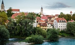 View of Kranj, a town in Slovenia, on a blue-sky day. A river runs past buildings in the old town.