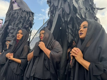 Women dressed in black shawls carry large grim reaper puppets