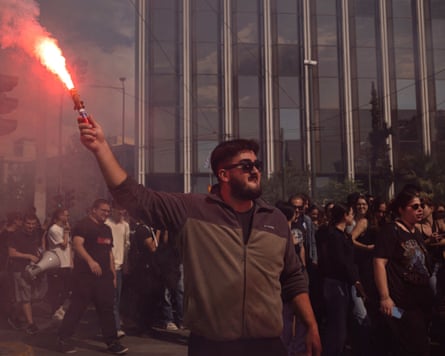 A university student holds a flare during a demonstration in Athens.