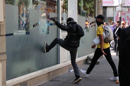 A protesters tries to kick in the window of a shop in Paris.