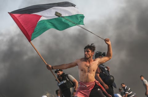 A man with slingshot and a Palestinian flag at the Gaza border