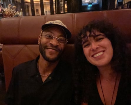 Stephen and Shahar sitting next to each other on a banquette and smiling at the camera
