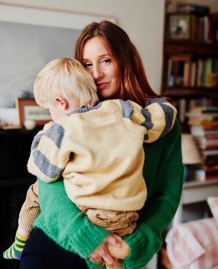 Morwenna Ferrier standing in a living room holding her son, who is now three