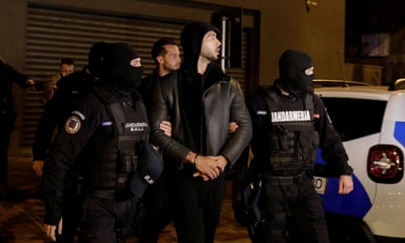 Andrew, au centre, et Tristan Tate sont escortés par des policiers devant la Direction des enquêtes sur le crime organisé et le terrorisme à Bucarest après avoir été détenus pendant 24 heures.
