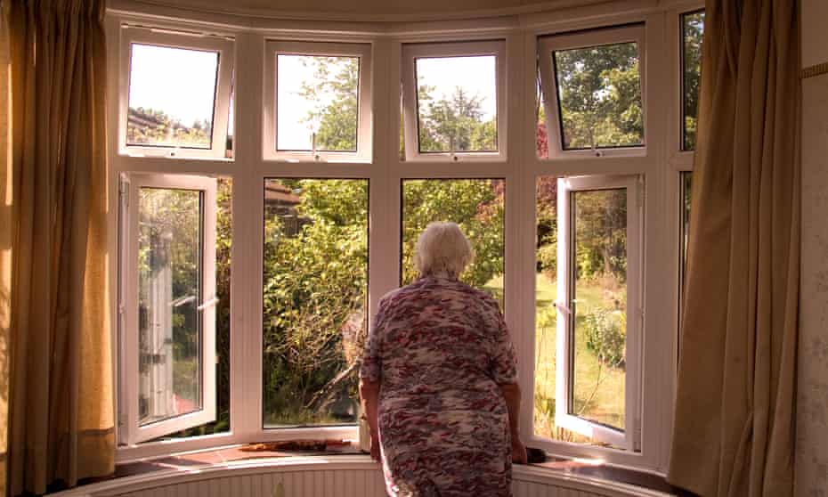 81 year old elderly woman looking out of her front room window