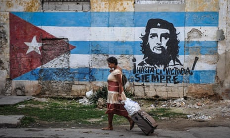 A woman walks by a mural with the Cuban flag and an image of revolutionary leader Che Guevara in Havana.