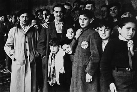 Men and boys wearing the Jewis star of David stand looking at the camera in this black-and-white picture.