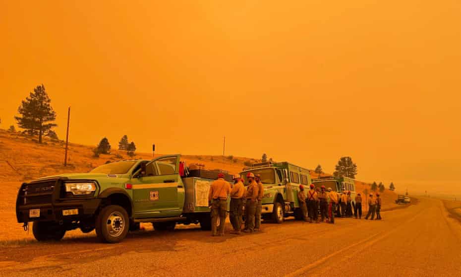 Smoke casts an orange haze as firefighters hold a briefing in the Black Lake, New Mexico, area on 11 May. 