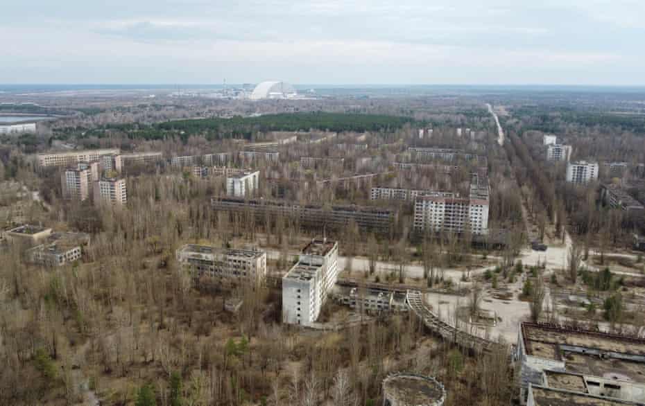 Une nouvelle structure de confinement sûre sur l'ancien sarcophage couvrant le quatrième réacteur endommagé, avec la ville abandonnée de Pripyat au premier plan.