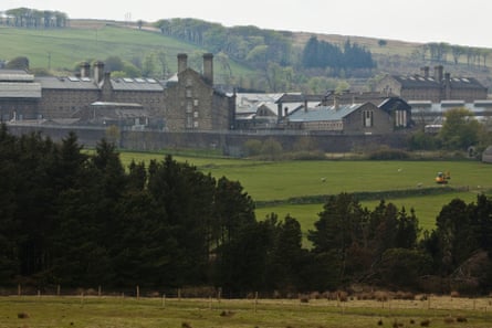 Grey prison buildings in a green landscape.
