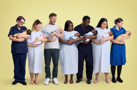 A line-up of new parents with their newborns flanked by medical staff