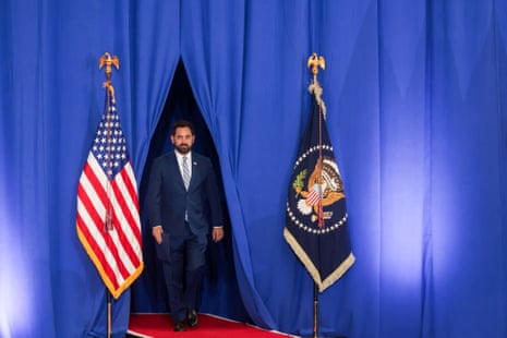 a man walks through a blue curtain on a red carpet