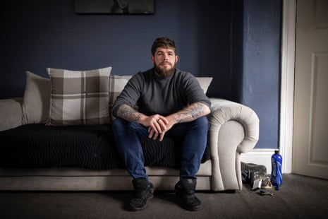 Josh Cook photographed at home in Huddersfield. He is sat on a sofa with his arms resting on his knees