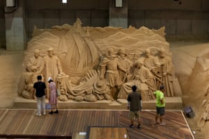 A drone shot of visitors looking at a sand sculpture that depicts the history of Japanese trade