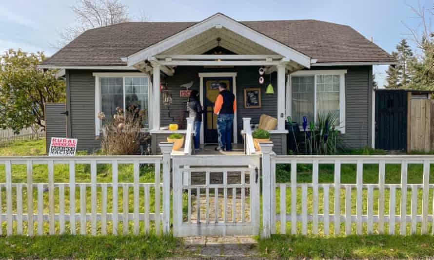 two people standing at the door of a grey and brown home