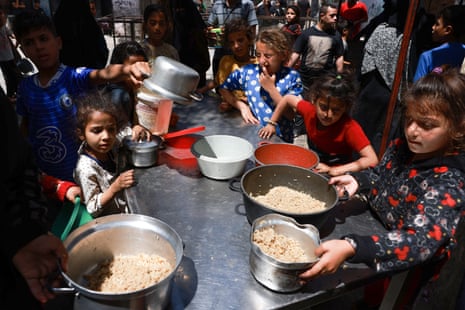Displaced Palestinian children line up to receive food in Rafah, on the southern Gaza Strip on 19 April 2024.