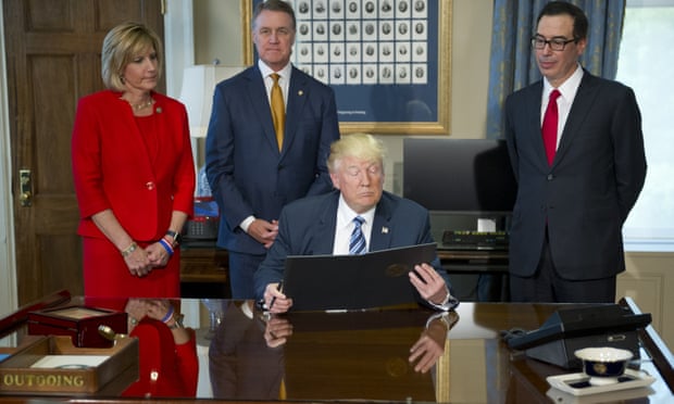 Donald Trump looks over the document prior to signing the first of three executive orders concerning financial services at the Department of the Treasury in Washington DC on 21 April 2017. 