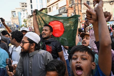 People wave Bangladesh’s national flag and raise their arms as they celebrate in the street