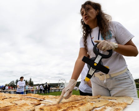 A woman measures the length of strudels on a table