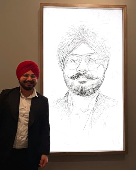 Tagarh, who is bearded and wearing a red turban, stands alongside his portrait, which has been produced in a charcoal-drawing style on a white background