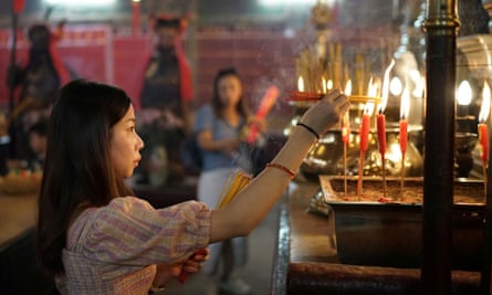 A woman burns incenses as she prays at Man Mo Temple in Hong Kong