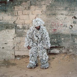Congolese artist Abdoulaye Kinzonzi Kiakanda posing in his water plastic bag costume in Selembao district, Kinshasa. In Kinshasa and throughout the country, itinerant street vendors sell sachets of drinking water on the arteries of the capital. Once used, these bags are thrown on the ground, causing mountains of waste. Abdoulaye recycled them into a suit.