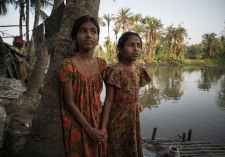Two girls listen by a river at an NGO meeting.