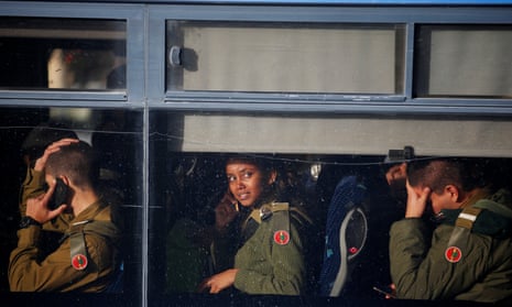 Israeli soldiers sit in a bus as they leave the scene