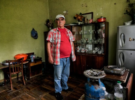 A man standing in a room with a gas cooker and fridge