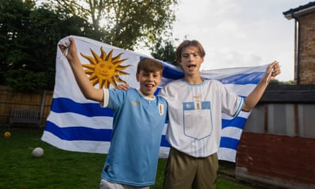 Nacho and Camilo Godoy wearing Uruguayshirts and holding a flag behind them in their garden