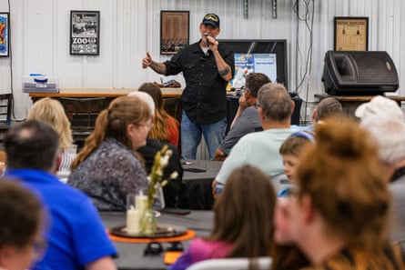 Senate candidate Dan Osborn speaks with a microphone to a seated audience at a town hall