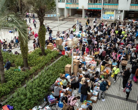 Aerial view of people gathered to hand out and receive supplies as some carry cardboard boxes full of items