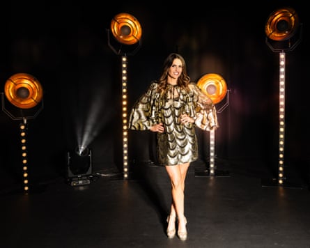 Ellie Taylor in metallic minidress with spotlights behind her