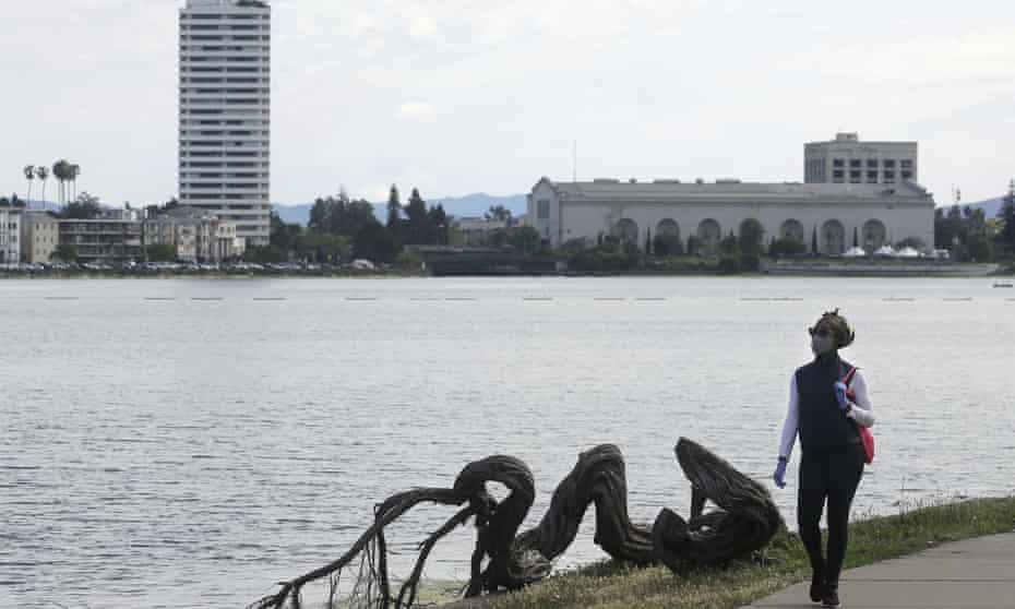 A woman wears a face mask while walking at Lake Merritt. Nooses were found hanging in trees in the area.