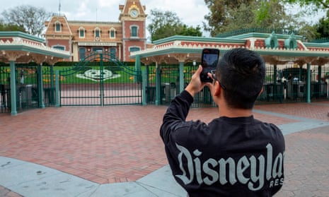 A man takes a photo outside the gates of the closed Disneyland Park in California.