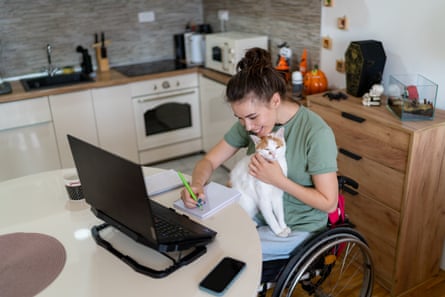 Happy disabled woman taking notes while enjoying with her cute cat at home office.