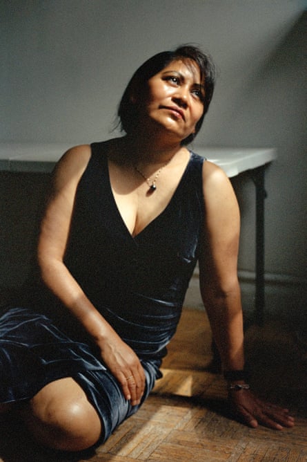 A woman wearing a velvet dress sits on the floor and gazes into the light