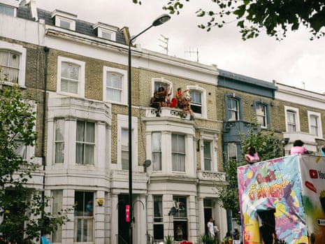 A group of people sitting on top of a bay window watching the carnival