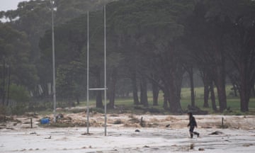 A man walks across a rugby field during heavy flooding in South Africa