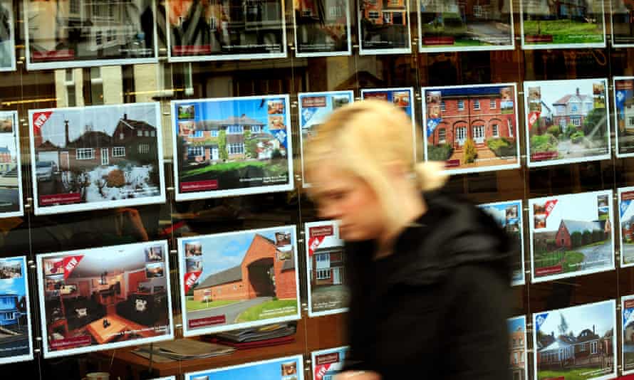 A woman walks past an estate agent’s window