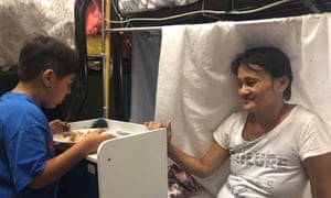 Neng and Jerry eat a meal in their tiny shared room.