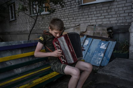 Fedya (13) plays his accordion outside the apartment building.