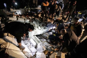 La gente observa cómo los rescatistas sirios (Cascos Blancos) recuperan a un hombre herido de los escombros de un edificio derrumbado tras un terremoto, en la ciudad fronteriza de Azaz.