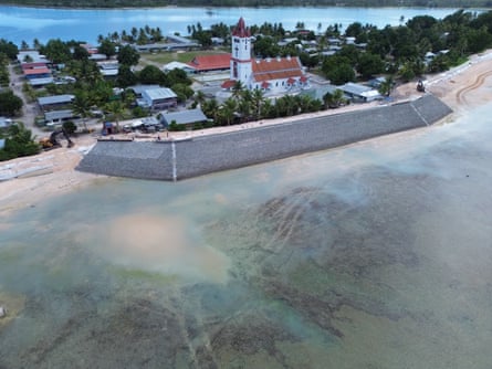A sea wall in front of a church and houses