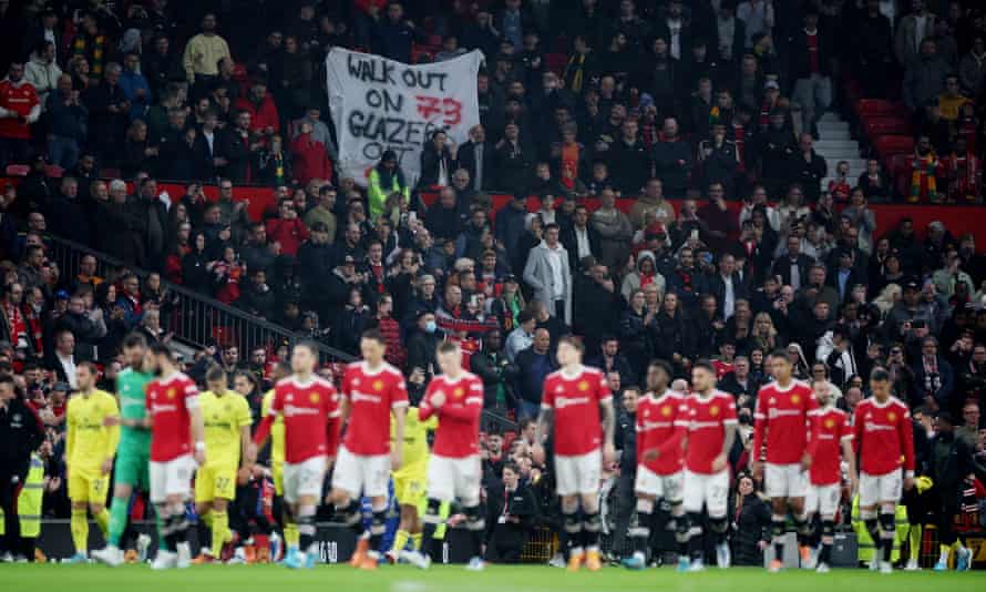 An anti-Glazer banner is seen in the stands as the players take the pitch.