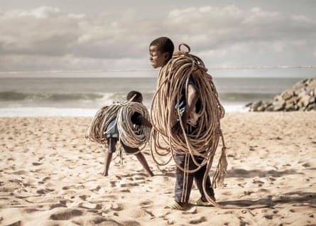 Two brothers carry heavy ropes as they go to work on the fishing boats