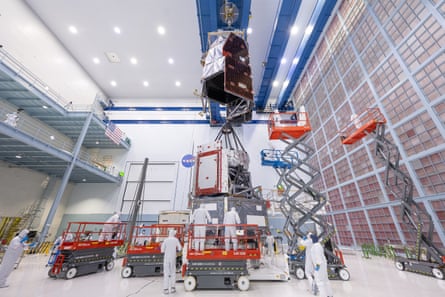 Technicians observe the Nancy Grace Roman Space Telescope’s solar panels in a cleanroom