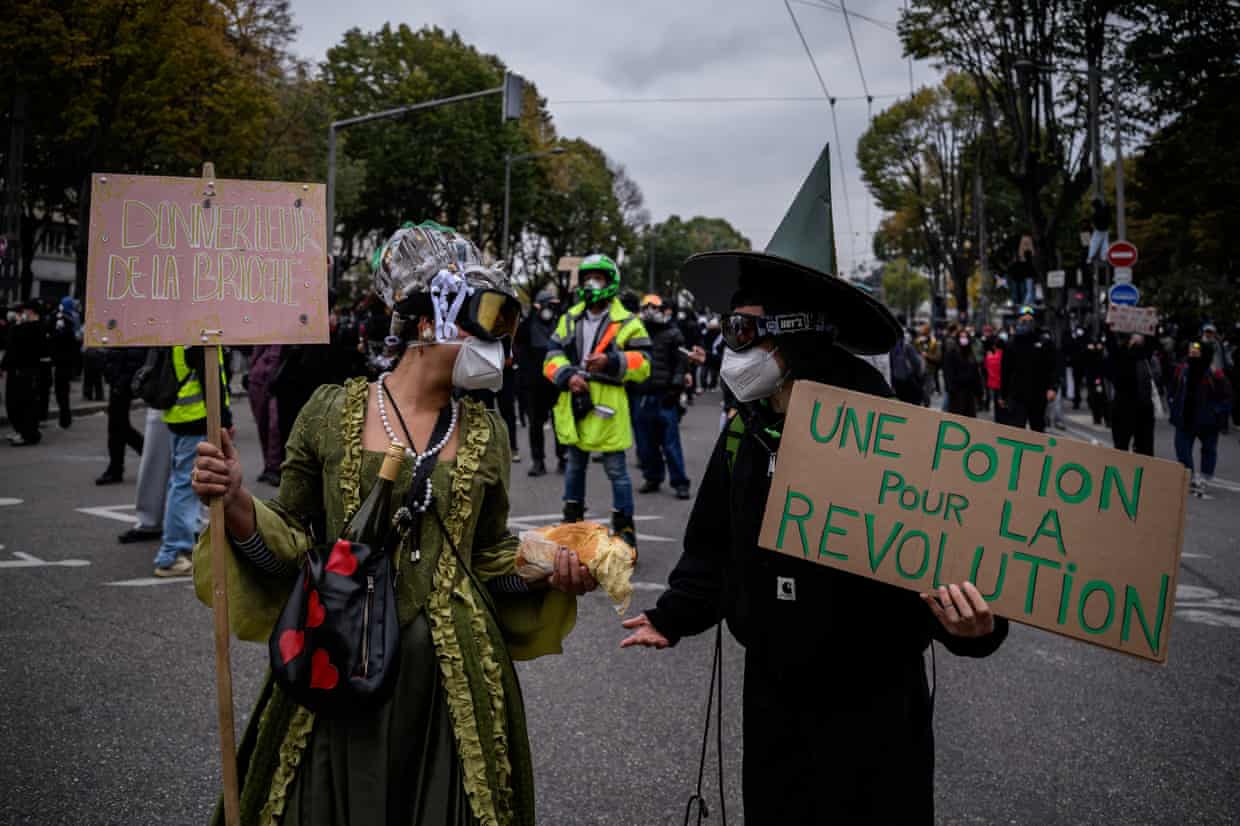 A protester dressed as Marie-Antoinette and another as a wizard hold handwritten placards during a demonstration