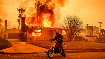 Smoke and flames engulf a location and a biker rides past