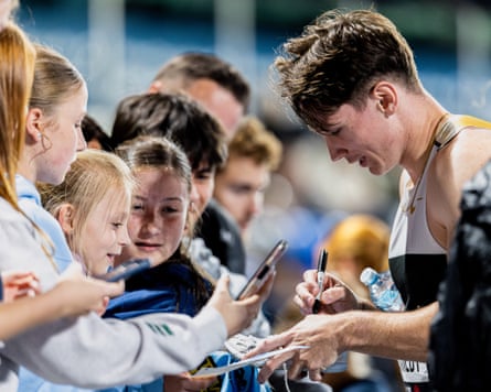 Lachlan Kennedy signs autographs after winning the 100m final at the Australian Athletics Championships